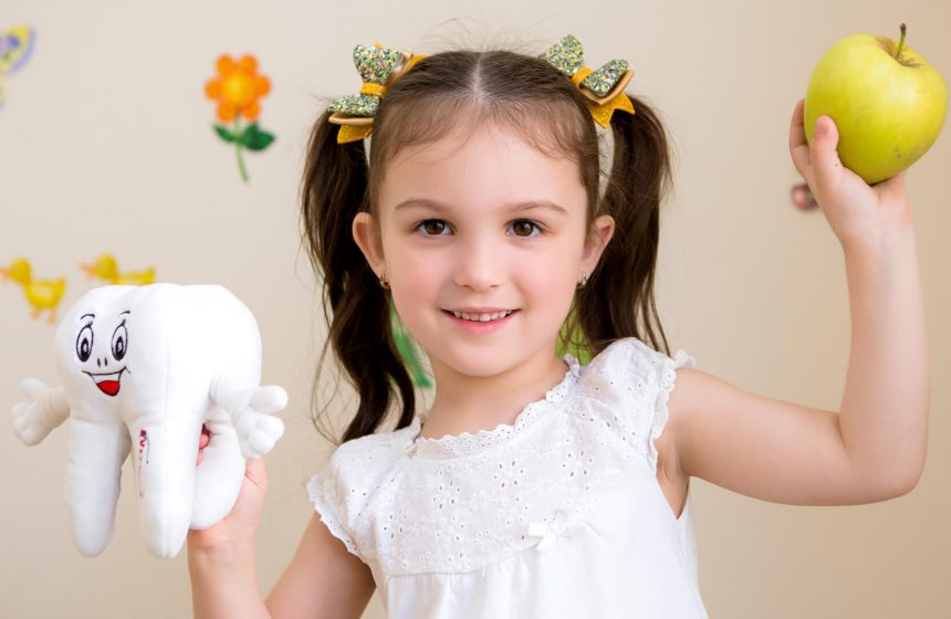 Little girl holding an apple and a tooth plush